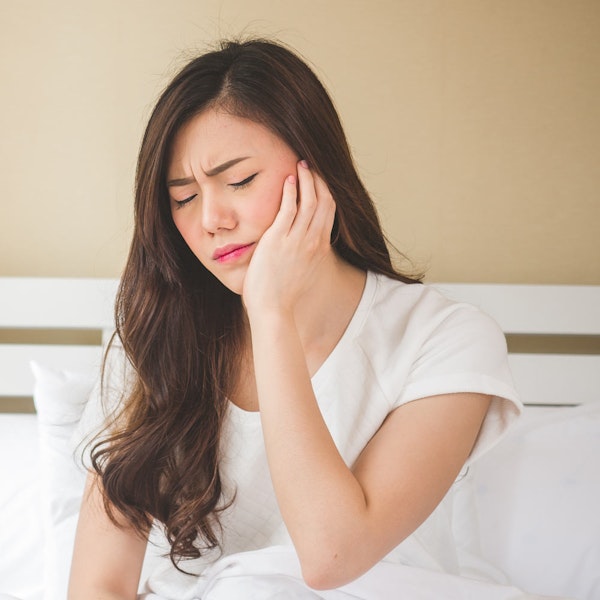 Long-haired woman rubbing jaw