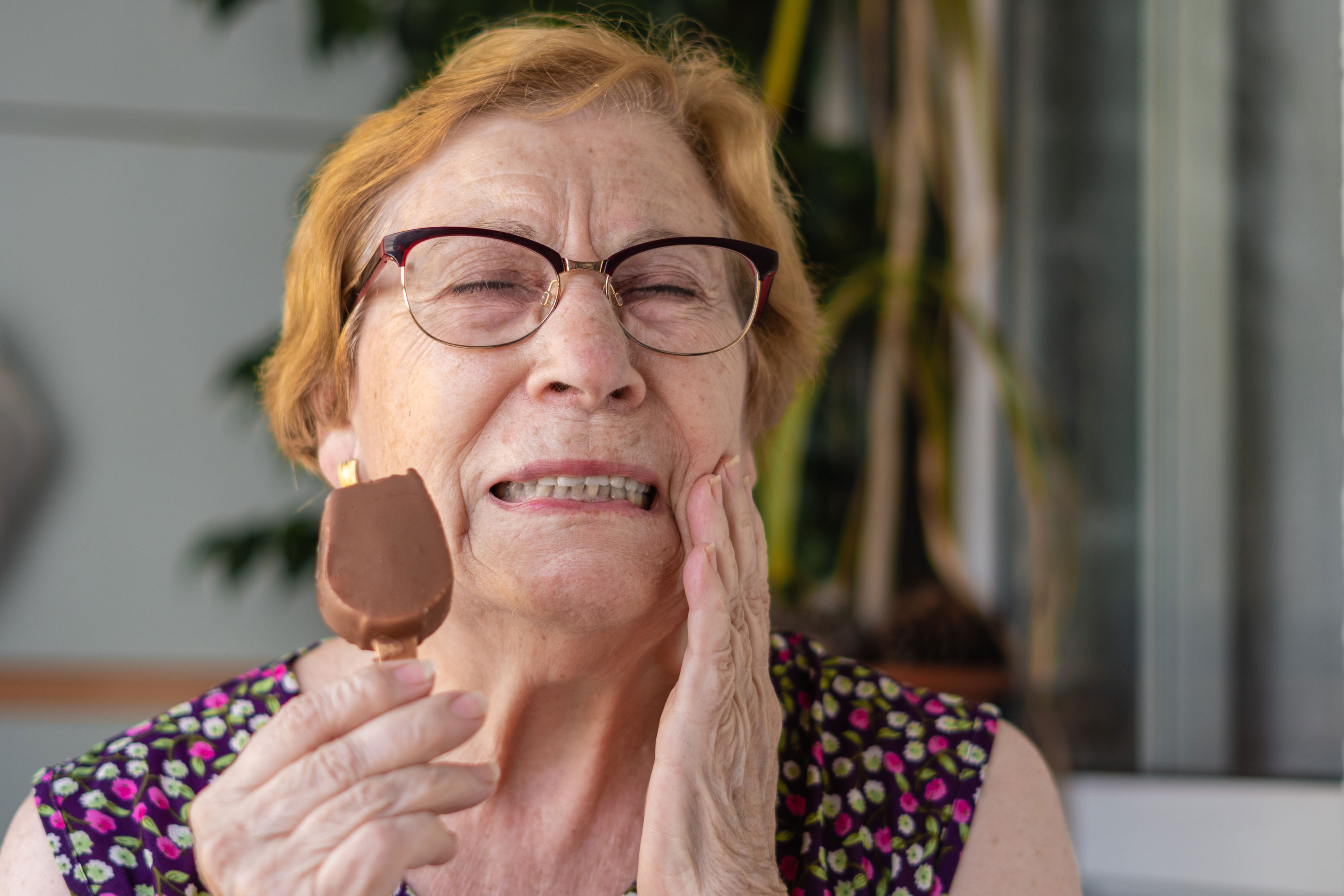 Older woman with a sore tooth while eating an ice cream bar