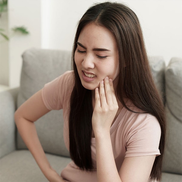 Young woman holding jaw in pain