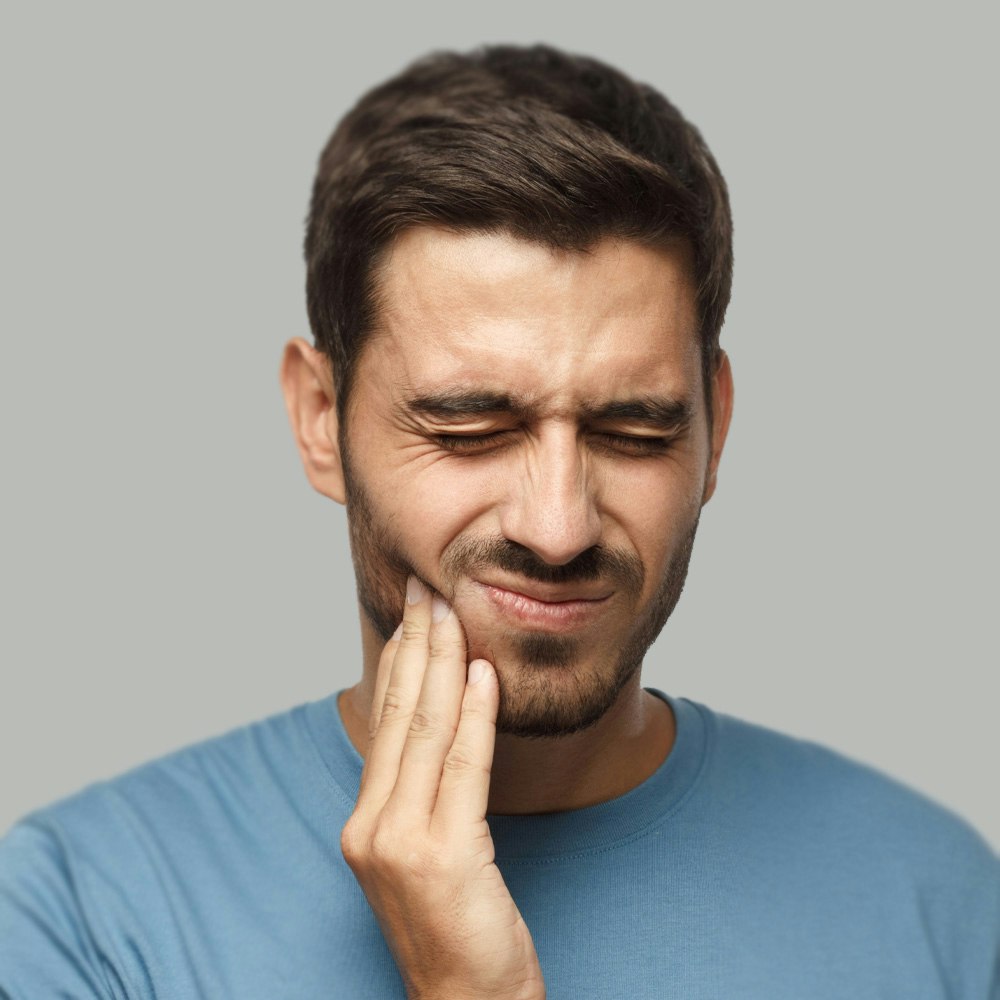 Wincing man holding jaw