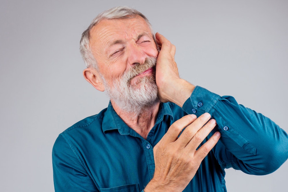 Elderly man holding jaw in pain