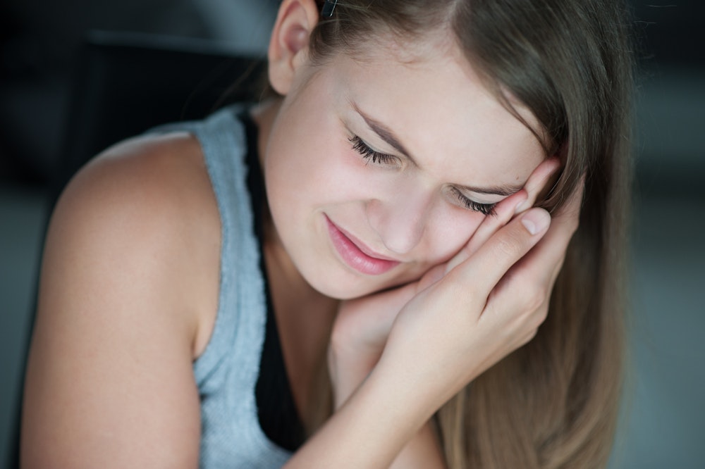 young girl clenching her jaw in pain
