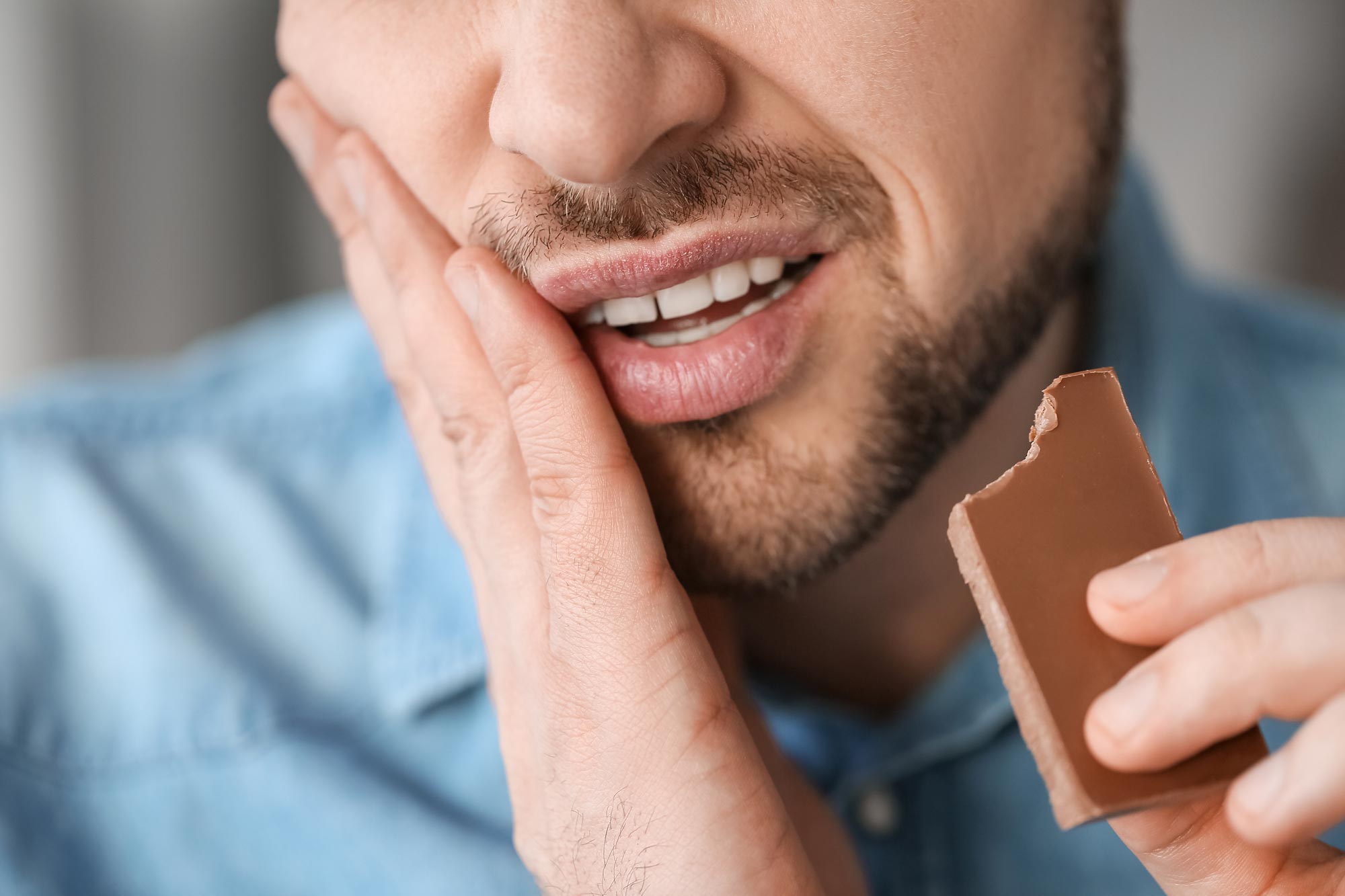 Man with sore tooth while eating some chocolate