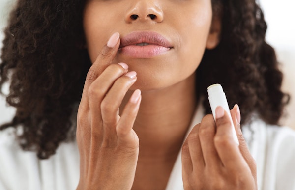 Woman applying lip balm to lips
