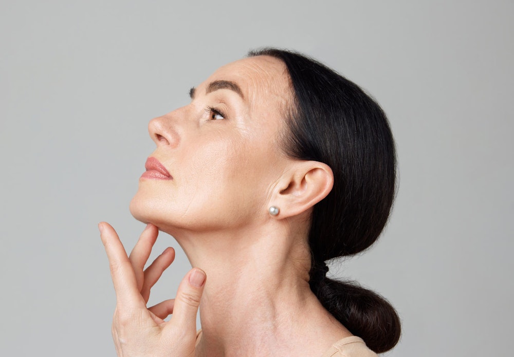 Side profile of mature woman touching her chin while looking up