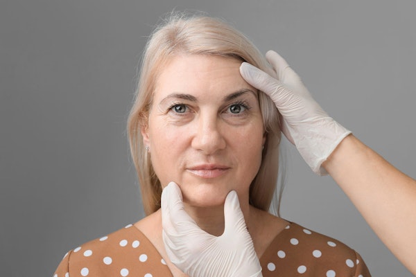 Woman with doctor's gloved hands examining face