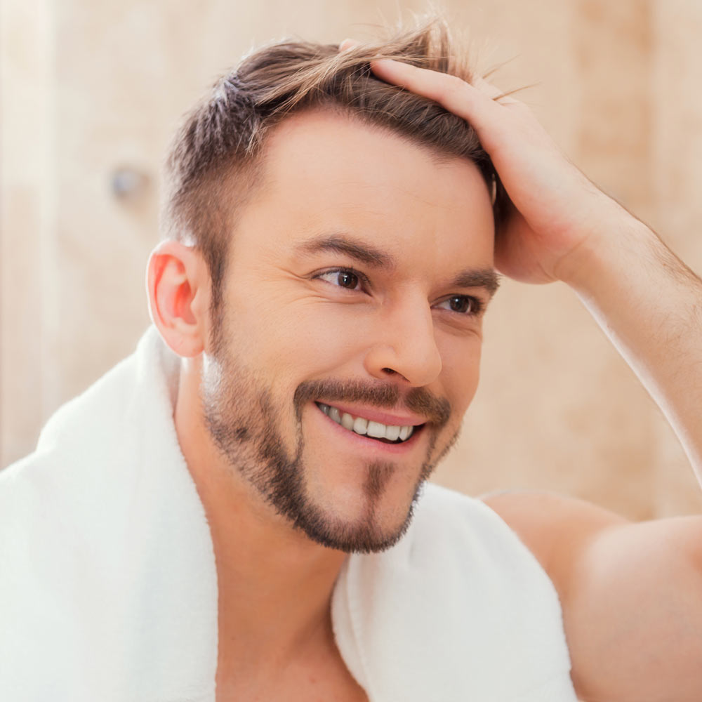 Smiling man pushing hair out of face