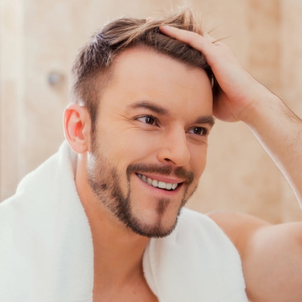 Smiling man pushing hair out of face