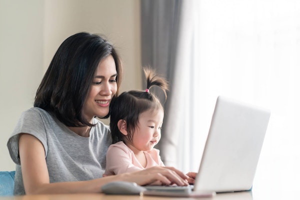 Mom holding baby while working remotely on laptop