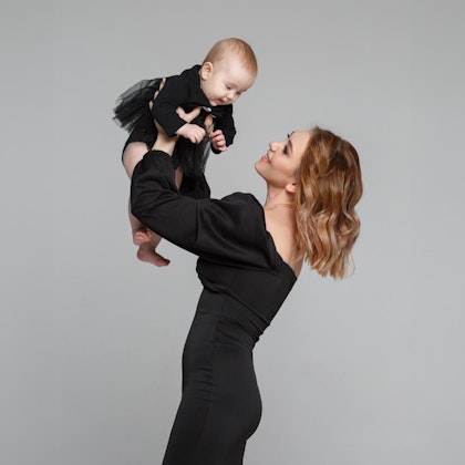 Woman in black bra holding up baby in black outfit