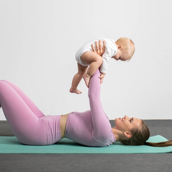 Woman lying down with liposuction holding up her baby