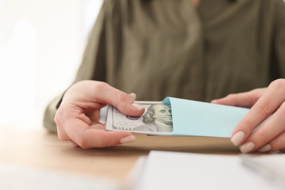 Person taking out a wad of money out of an envelope