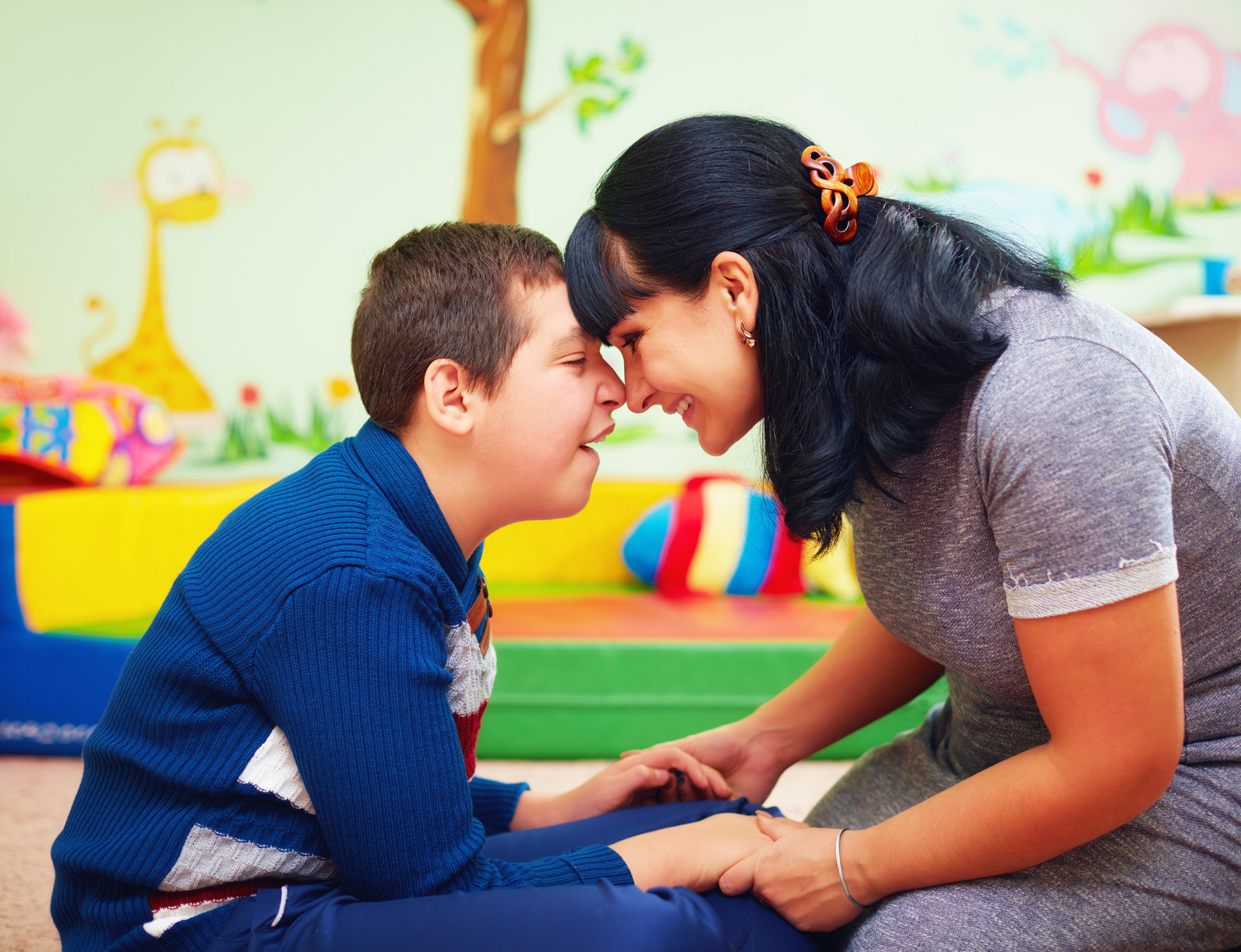 Mother and child with disability holding hands and heads touching
