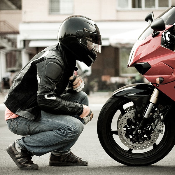 Motorcycle rider examining wheel