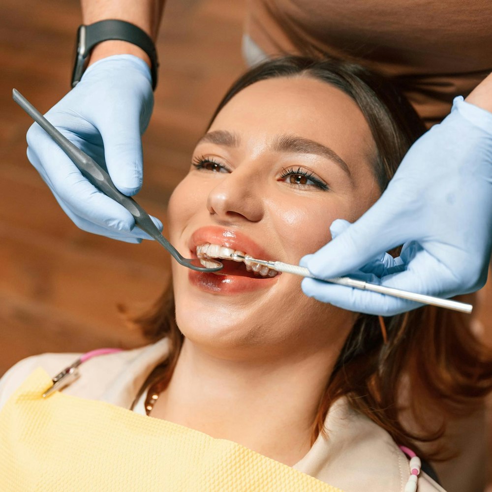 Smiling woman wearing clear aligners while dentist checks teeth