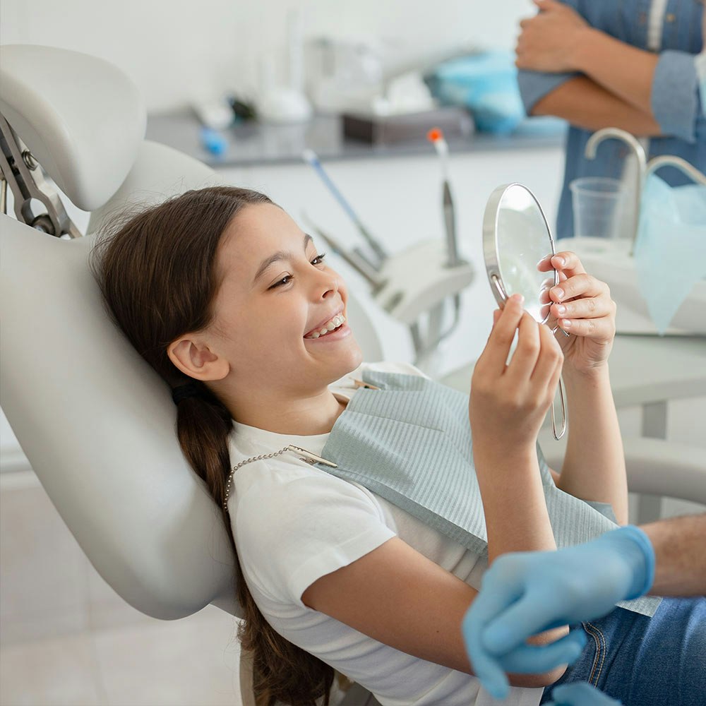 Young girl at dentist smiling in a mirror
