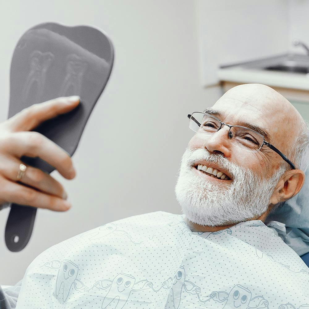 Older man at dentist smiling in a mirror