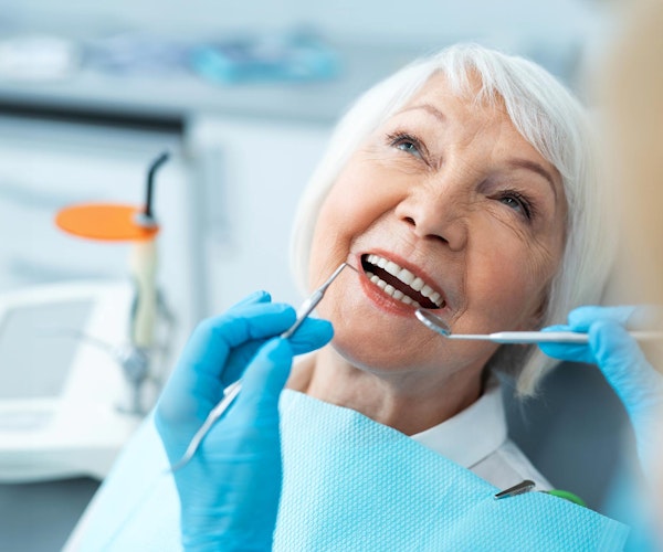 Smiling mature patient with dentures in a dental exam