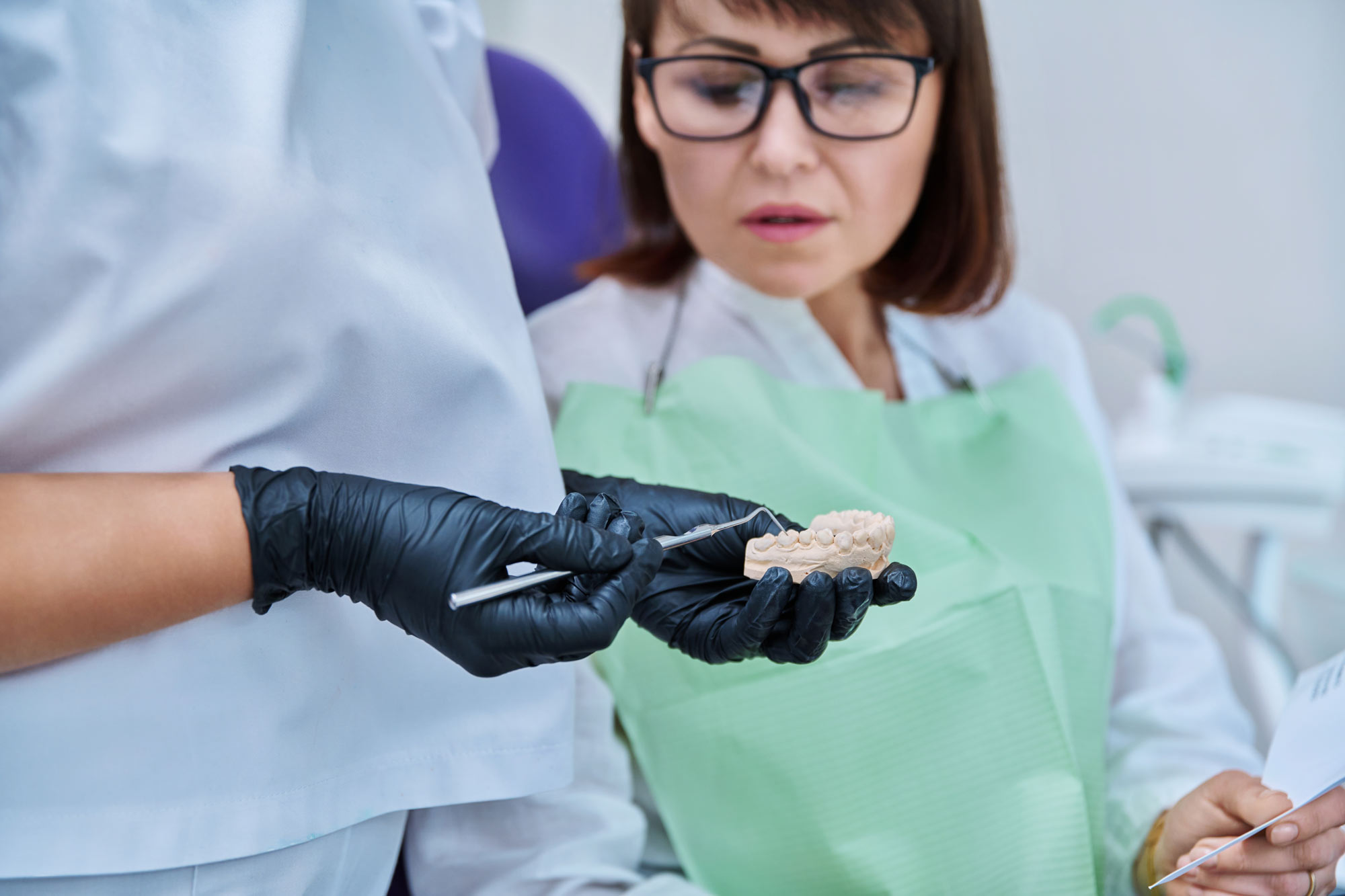 Dentist showing mature female patient a tooth model