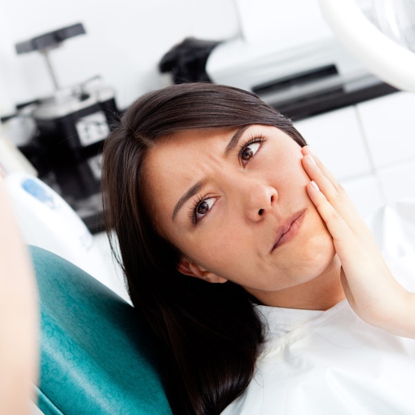 Woman holding jaw in discomfort at the dentist's
