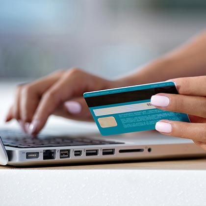 Woman on laptop holding credit card