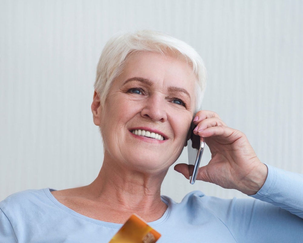 woman on the phone booking dental implants consultation