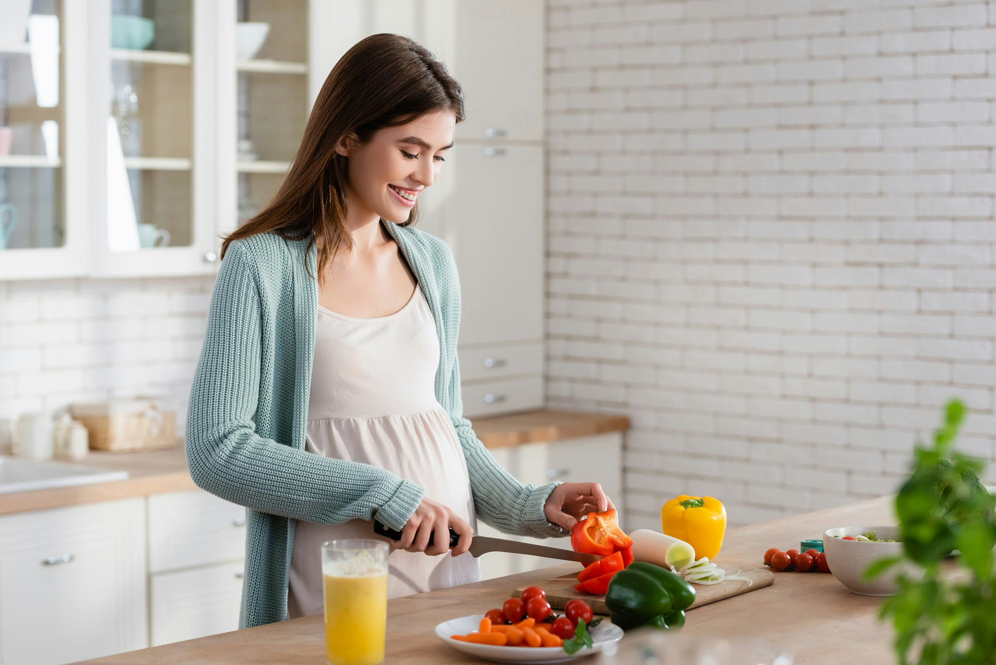 Pregnant woman cutting vegetables for meal prep