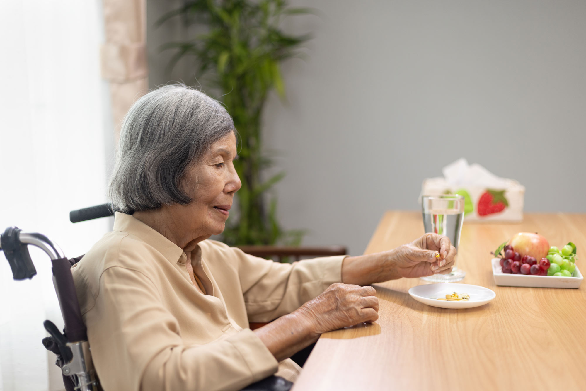 elderly woman in a wheelchair sitting at a table and eating
