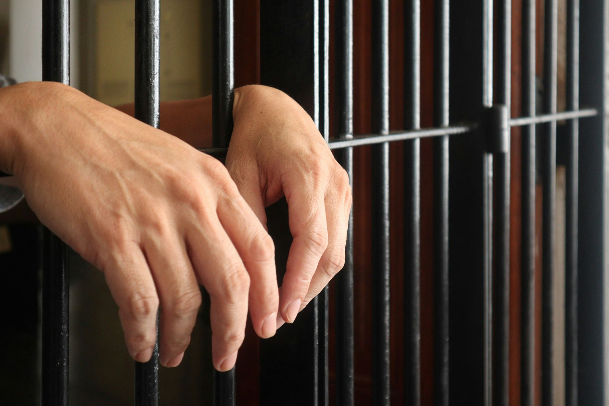 man's hands sticking out of jail cell