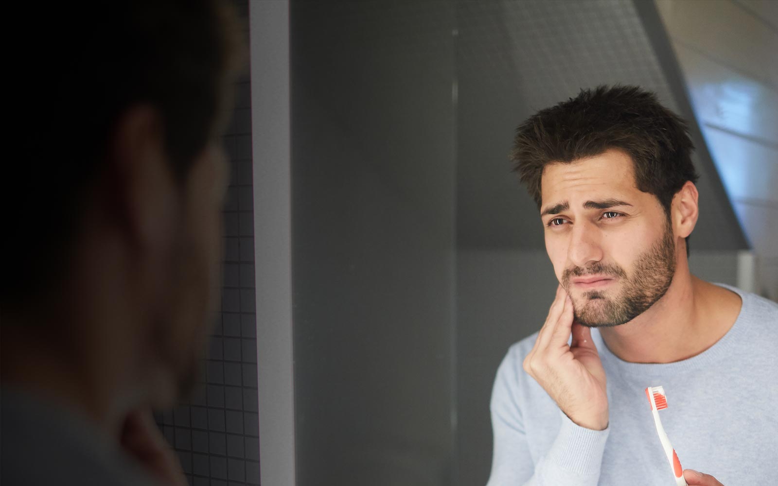 Guy with dental pain while brushing teeth