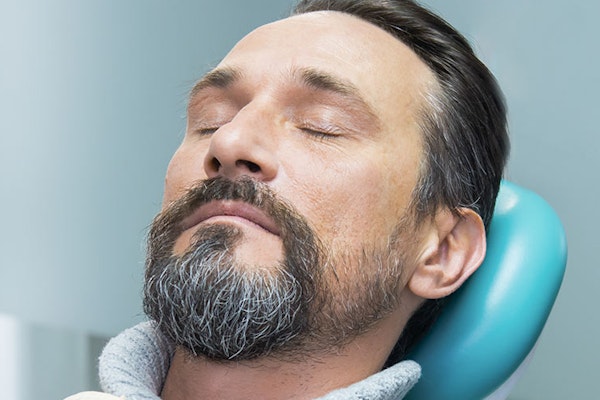 Sedated man sitting in dentist chair