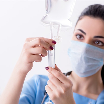 A nurse is setting up a fluid bag for IV sedation
