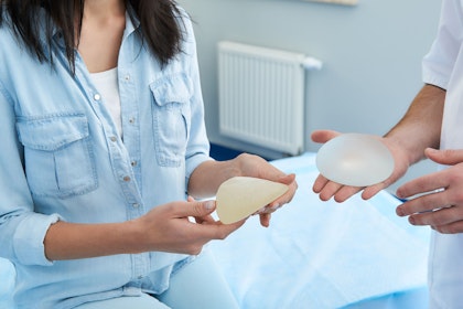 Surgeon and patient holding breast implants