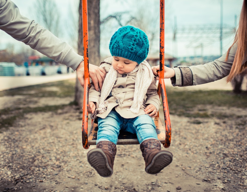 Two sets of hands pushing child in swing