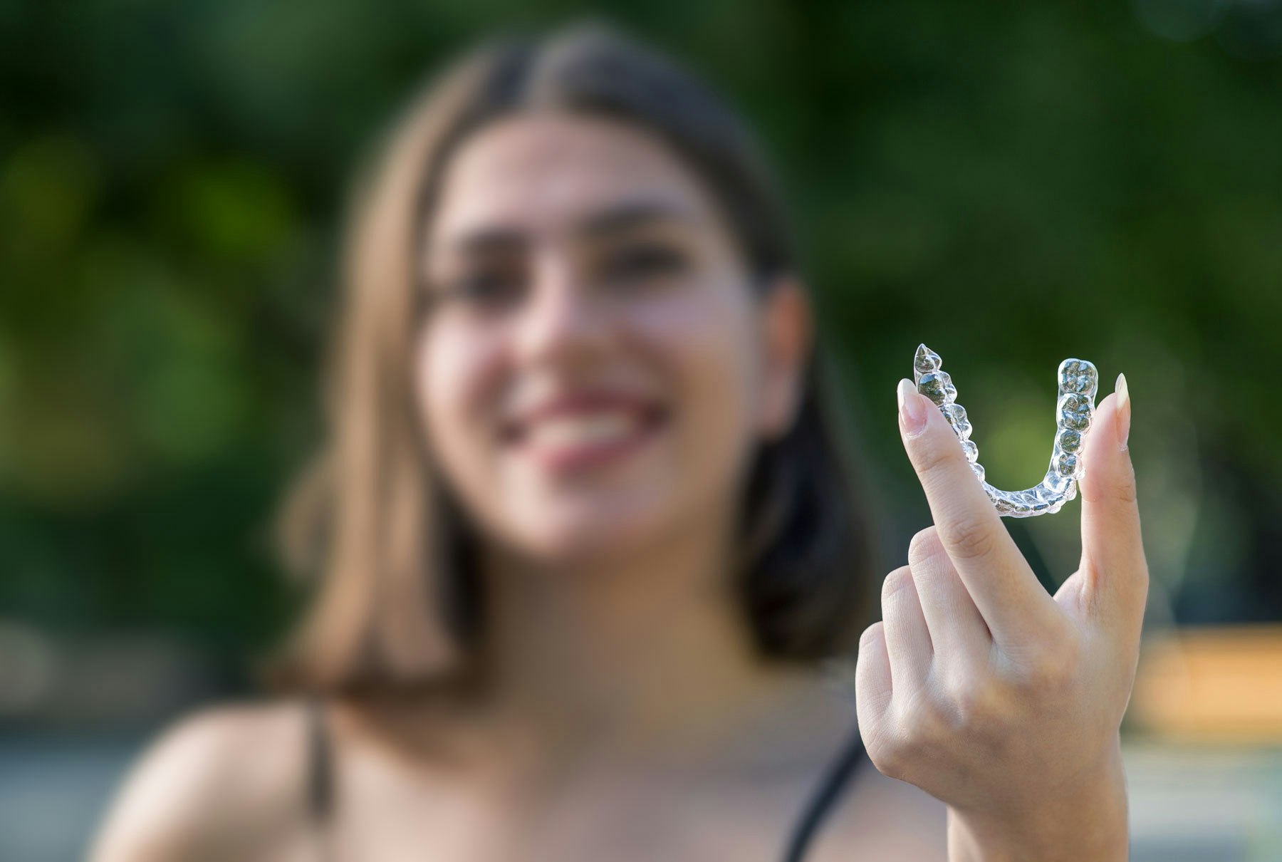 Woman holding up Invisalign tray