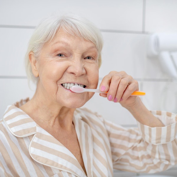 Mature woman with dental implants brushing teeth