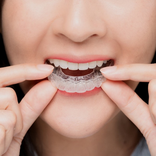 smiling woman about to put on Invisalign