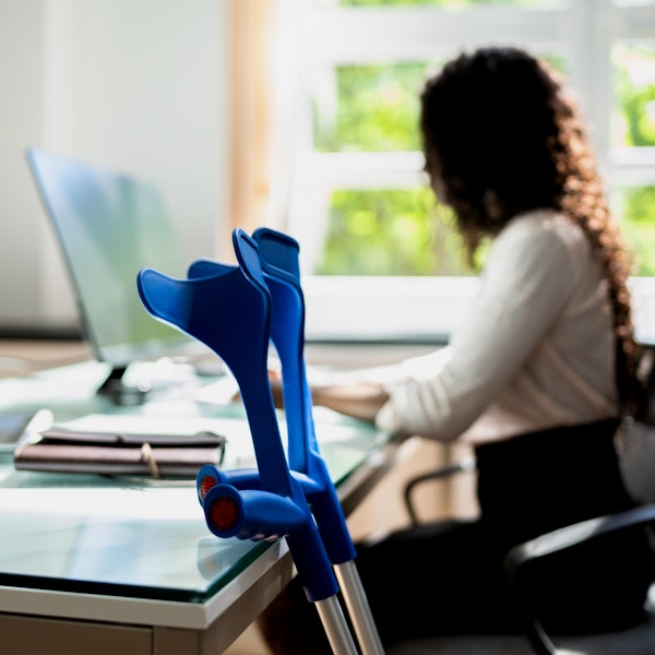 Woman working at a computer with crutches nearby