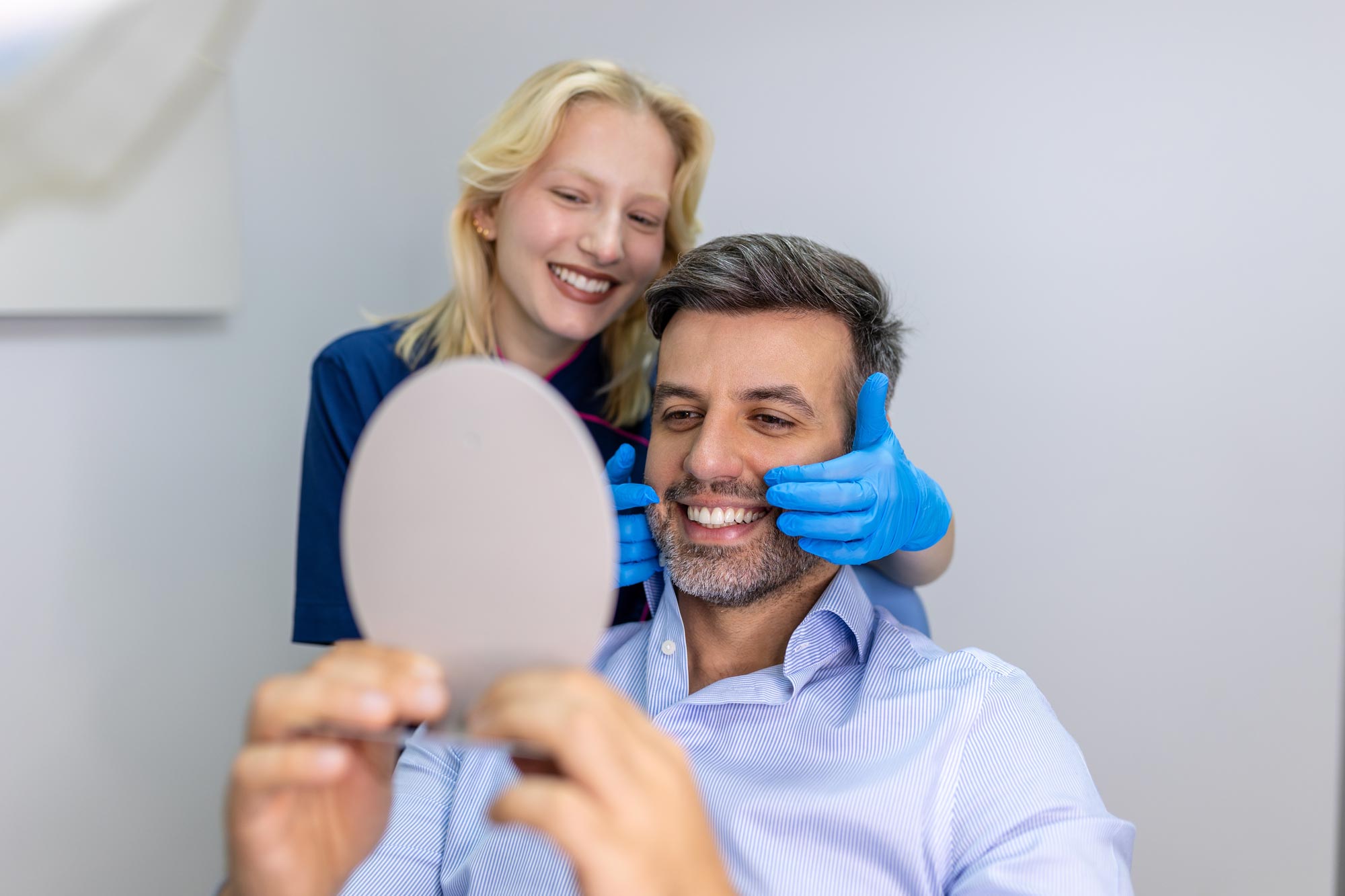Happy dental patient looking in the mirror after a cleaning