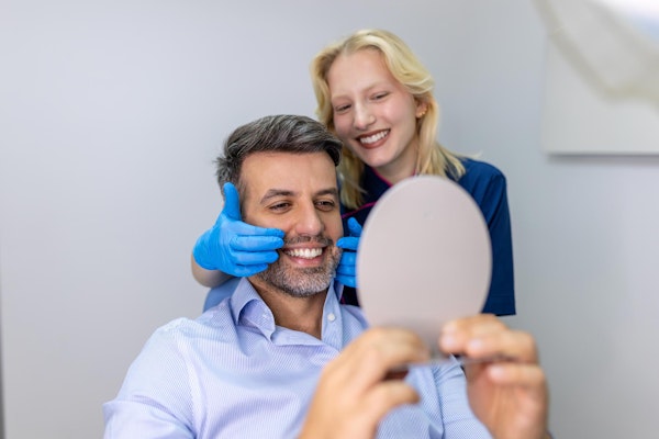 Happy dental patient looking in the mirror after a cleaning