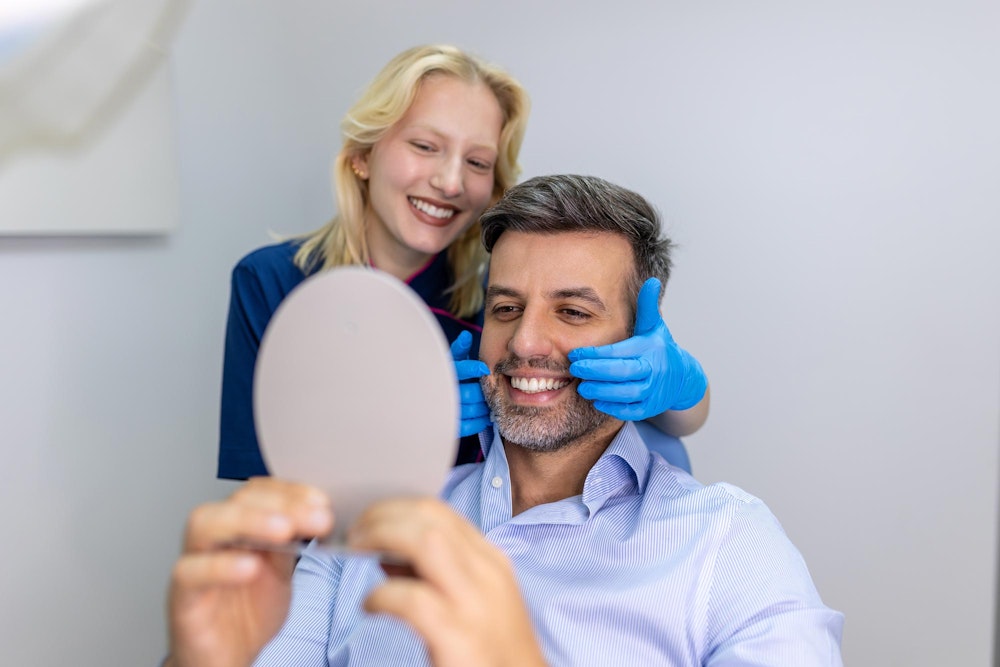 Happy dental patient looking in the mirror after a cleaning