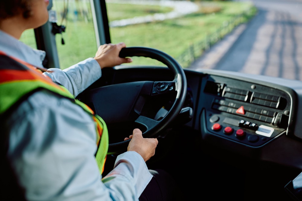 Bus driver wearing safety vest steering a commercial vehicle