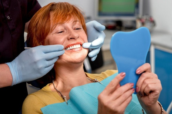 Smiling dental patient looking in mirror