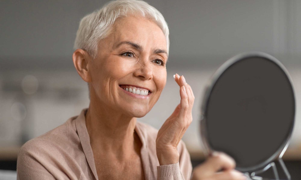 Mature woman looking at face in the mirror