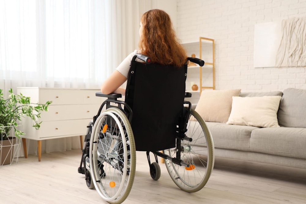 Back of young girl in wheelchair in house