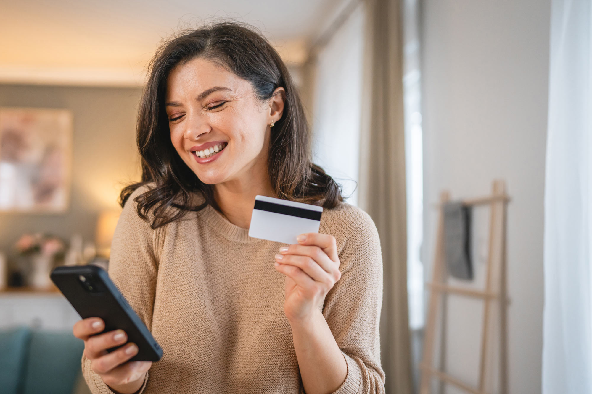 woman holding credit card paying on a phone
