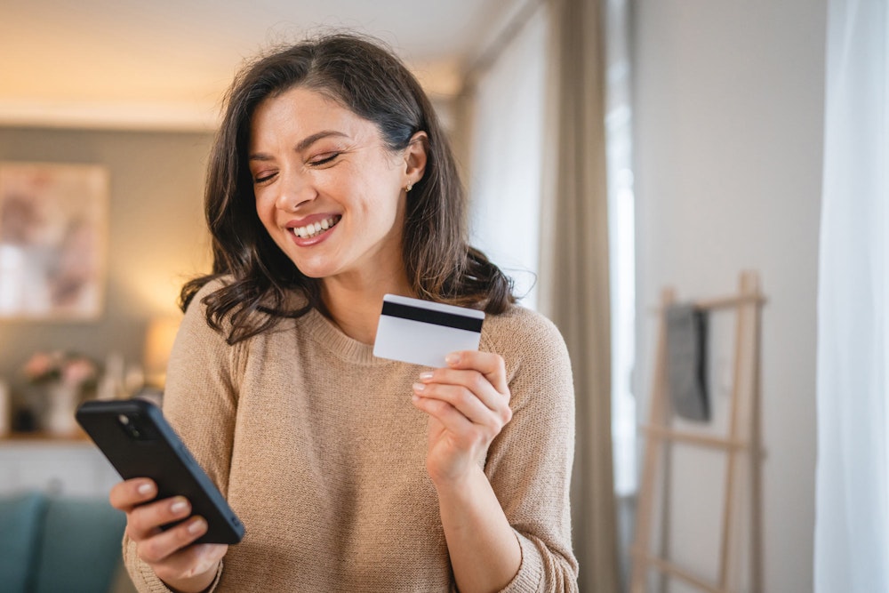 woman holding credit card paying on a phone