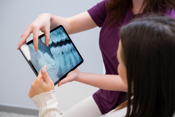 Woman being shown x-ray of her teeth on a tablet