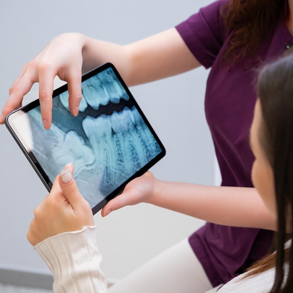 Woman being shown x-ray of her teeth on a tablet