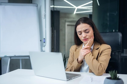 Working woman holding jaw in pain